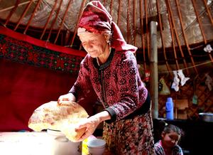 2020. Narun Oblast, Kyrgyzstan.  A woman breaks bread at a nomad camp. © Igor Kovalenko / FAO.